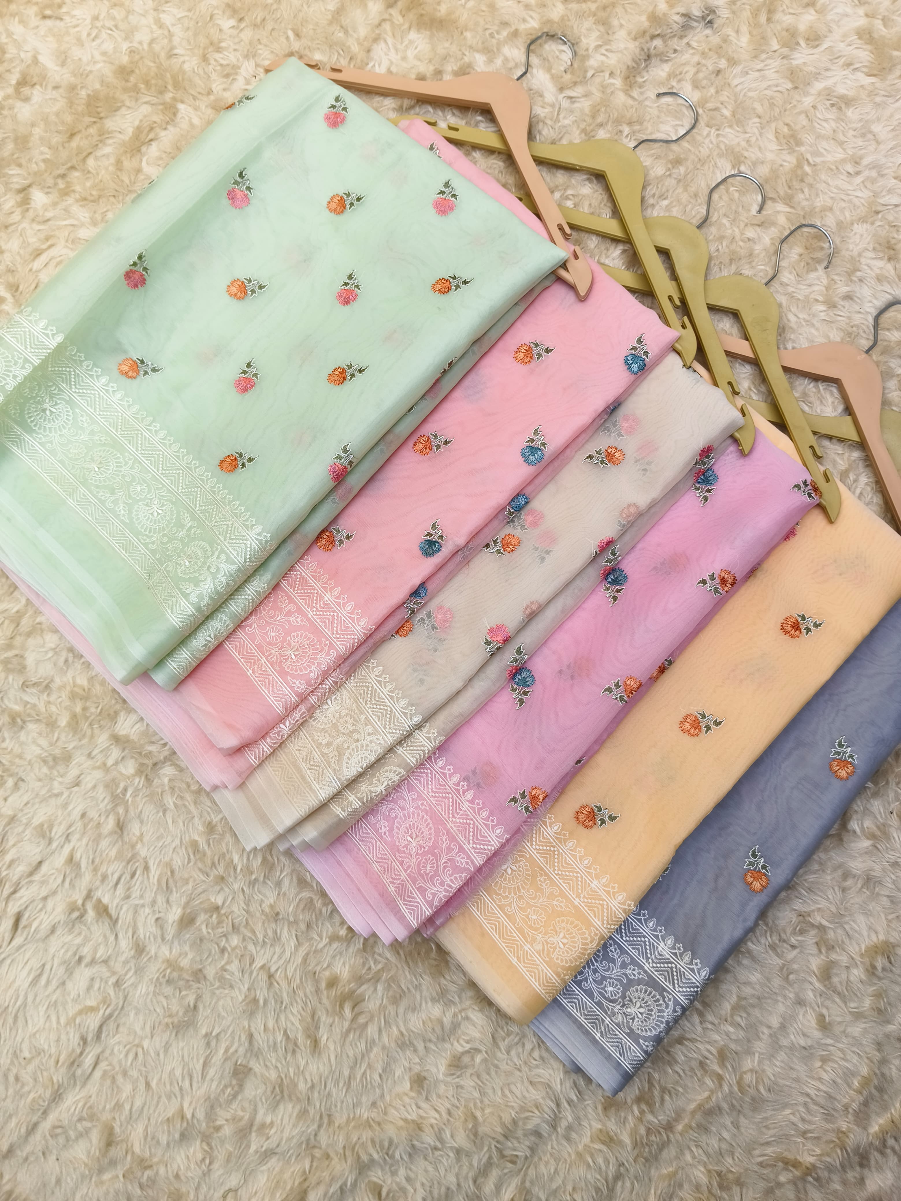 Set of colorful saree swatches with floral patterns on a textured surface