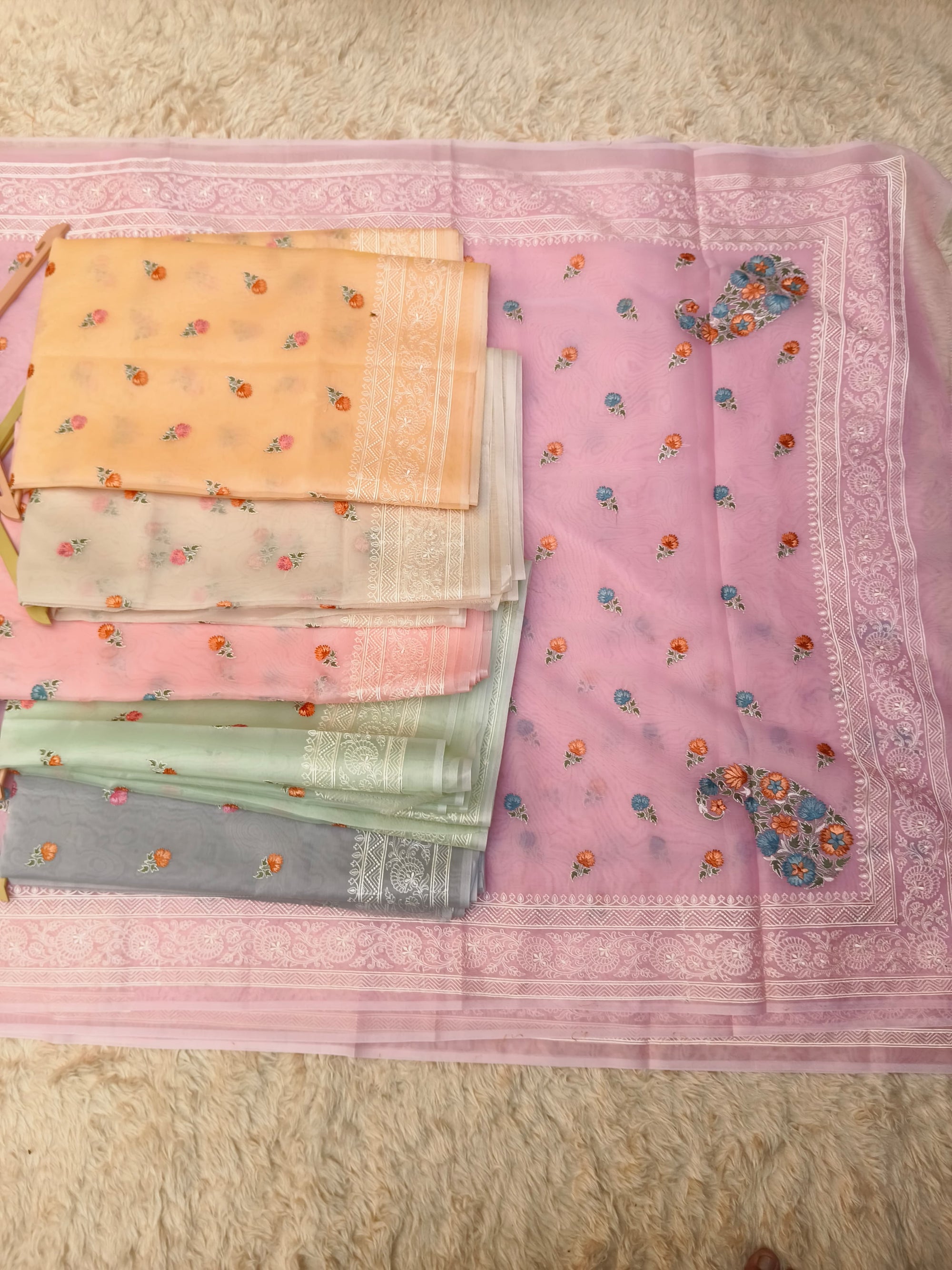 Set of colorful saree swatches on a pink fabric background