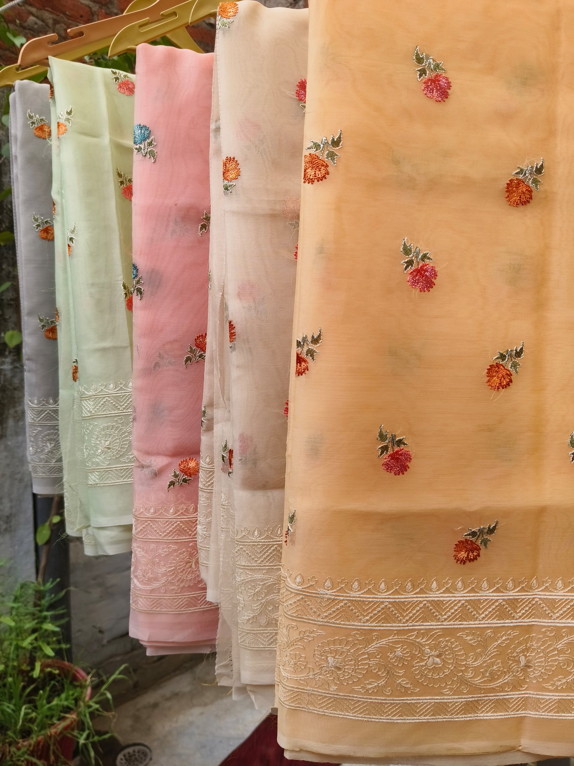 Set of saree samples with floral patterns on a hanger 