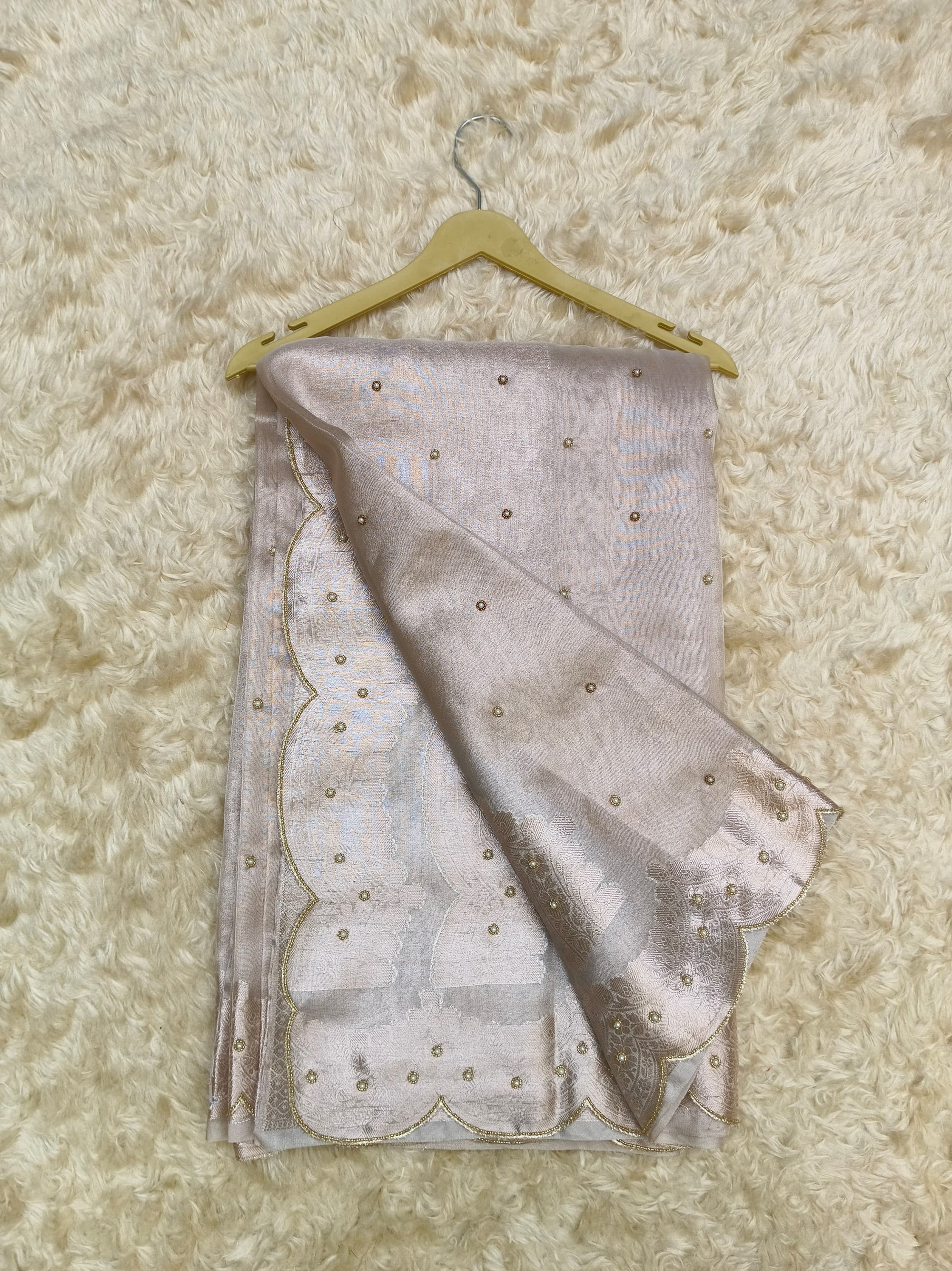 Folded saree with gold accents on a textured beige surface