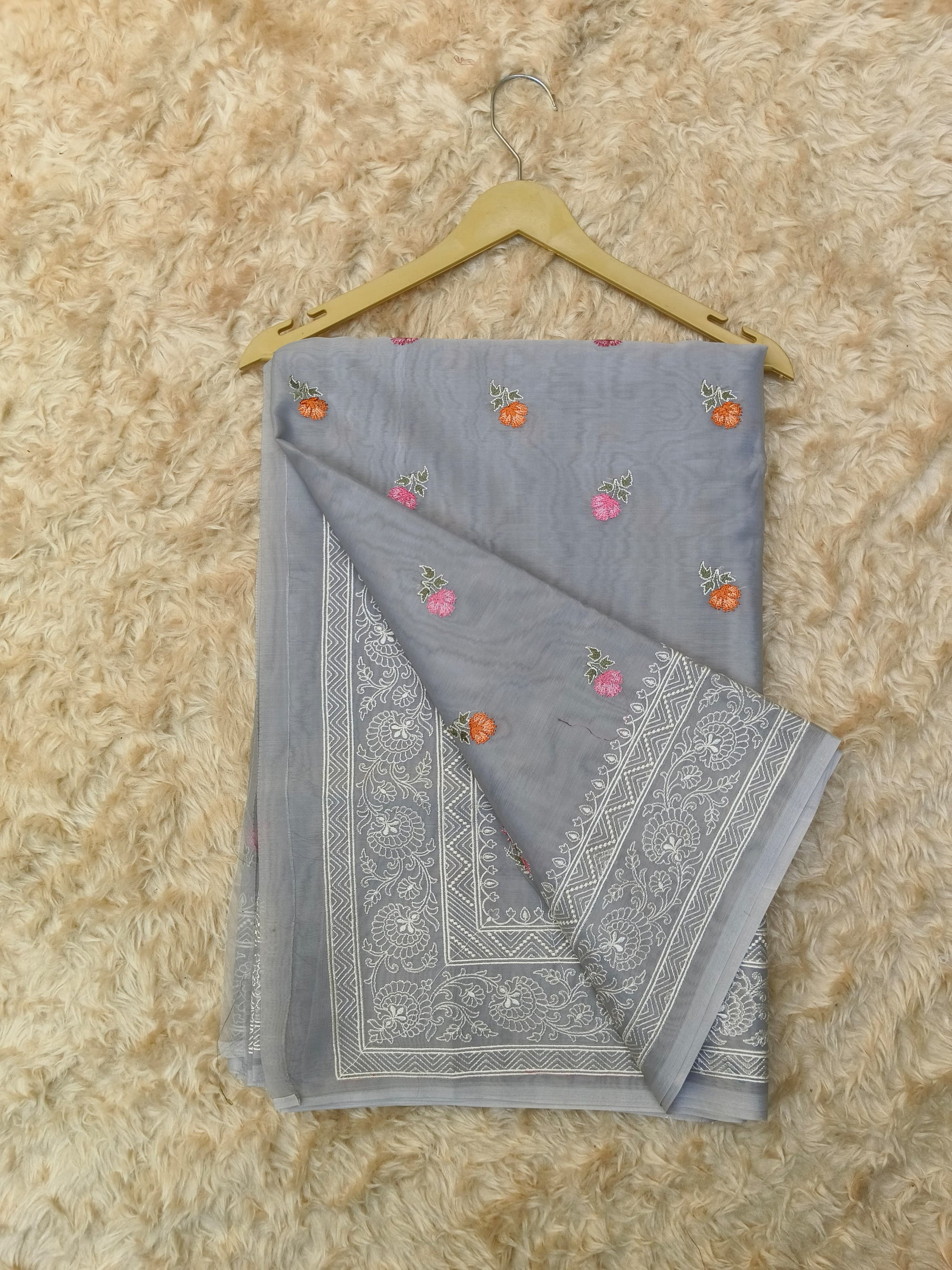 Gray saree with floral embroidery on a beige surface